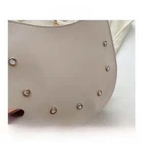 Close-up of beige saddle bag featuring sparkling rhinestones and a gold chain strap