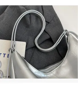 Detail of silver metallic crescent bag with braided straps and quilted texture finish