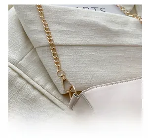 Detailed macro of cream faux leather saddle bag with gold chain and diamond buckle