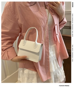 Close-up of white lychee pattern mini crossbody bag with gold chain strap on model