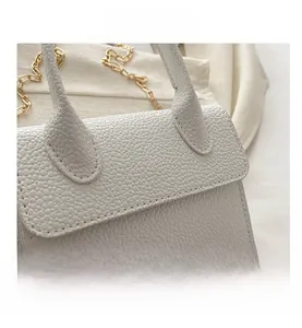 Close-up of white lychee pattern leather handbag with gold chain strap detail
