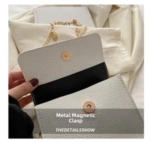 Detail of the golden magnetic hardware snap on a white litchi pattern leather handbag