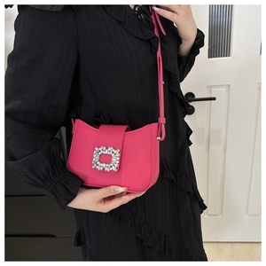 Detail of a bright pink leather handbag with a large sparkling rhinestone buckle