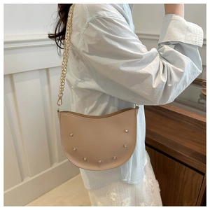 Close-up of beige crescent bag with rhinestone inlay and detachable gold chain strap