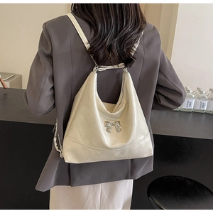 Chic cream leather bucket backpack with silver bow detail shown on a model