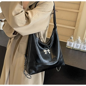 Versatile black pebbled leather bucket bag with silver bow accent and chain strap