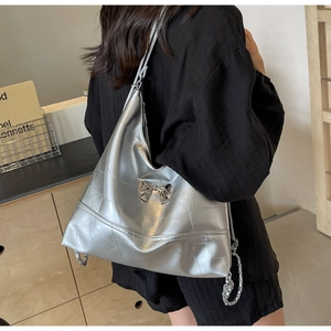 Detail of silver metallic bucket bag featuring quilted geometric patterns and bow decoration