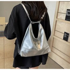 Silver metallic bucket bag with quilted patterns and bow detail worn as a backpack