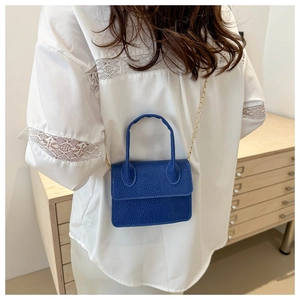 Détail d'un sac bleu roi à motif litchi avec bandoulière en chaîne dorée métallique