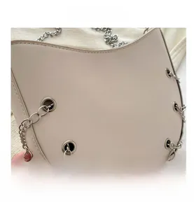 Close-up of cat-eared crossbody bag featuring silver chain hardware and smooth beige PU leather