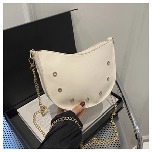 Close-up of a white hobo bag featuring crystal accents and a gold chain shoulder strap