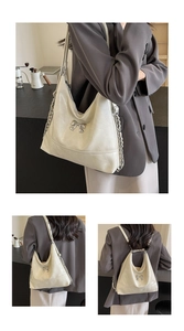 Detail of cream white leather tote bag with silver butterfly charm and chain strap
