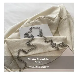 Close-up of the metal chain strap on a cream leather shoulder bag with sleek stitching