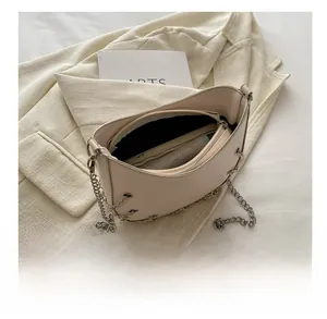 Interior detail of creamy leather shoulder bag with zipper pocket and metal chain links