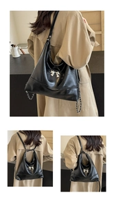 Detail of black leather hobo bag with silver butterfly and versatile shoulder straps