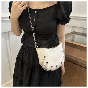 Close-up of white semi-circle crossbody bag with silver chain and stud details on a model