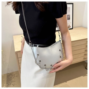 Close-up of metallic silver crescent bag featuring chic chain tassels and eyelet details