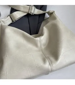 Close-up of beige tote bag with large square quilted pattern and wide strap