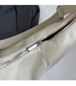 Close-up of smooth silver metal zipper and textured checkered leather tote bag