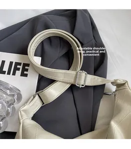 Detail view of the adjustable strap and silver buckle on a beige quilted tote bag