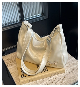 Détail du sac hobo en PU crème avec décoration papillon argentée sur du marbre