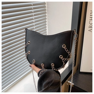 Detail of black crescent moon bag with silver eyelets and punk style chain fringe