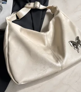 Détail du sac crème en PU souple avec gaufrage floral et pendentif papillon argenté