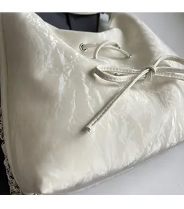 Close-up of silver pleated tote bag with bow drawstring detail and metal chain strap