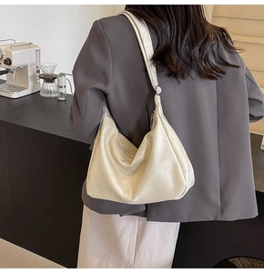 Detail of quilted ivory crescent bag showing smooth stitching and silver zipper closure