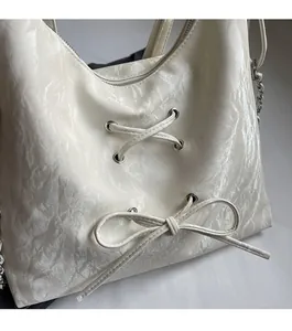 Close-up of cream pleated texture bag with metallic eyelets and bow details