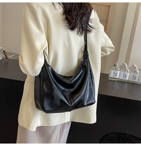 Close-up of black oversized shoulder bag with quilted stitching on a female model
