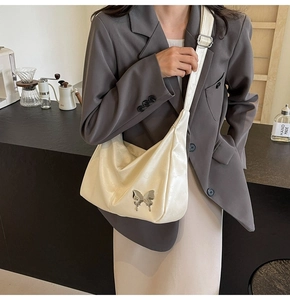 Détail du sac demi-lune en similicuir crème avec boucle papillon argentée et bandoulière