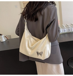 Détail d'un sac hobo en PU beige avec un papillon métallique argenté sur le côté