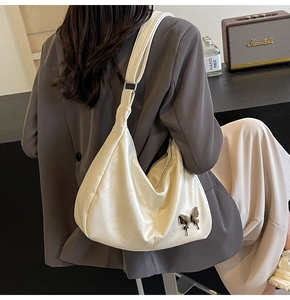 Détail du sac hobo en PU ivoire avec un ornement papillon métallique élégant