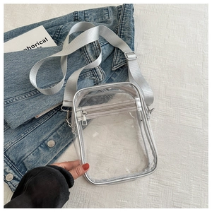 Transparent PVC crossbody bag with silver trim and adjustable strap on denim jacket