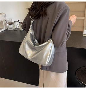 Detail of silver metallic tote bag featuring geometric stitching and metal ring strap