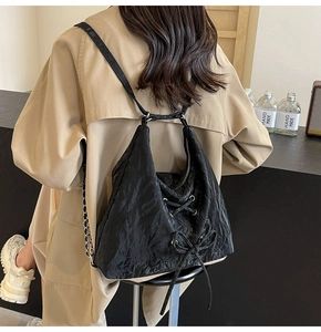 Detail of black pleated PU leather backpack with bow tie lacing on a model