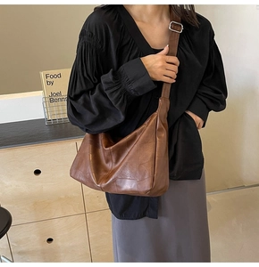 Detail of dark brown leather hobo bag with stitching and adjustable wide shoulder strap