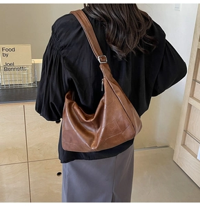 Detailed close-up of brown leather tote bag showing soft texture and contrast stitching
