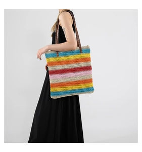 Dettaglio della borsa tote intrecciata a righe colorate con manici in pelle marrone scuro