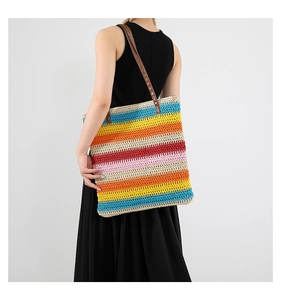 Borsa tote intrecciata a righe arcobaleno con manici in pelle su abito estivo nero