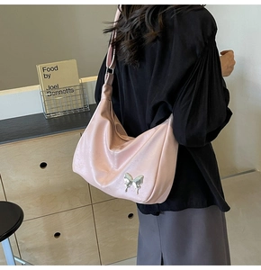 Détail du sac à bandoulière en similicuir rose avec ornement papillon en métal argenté