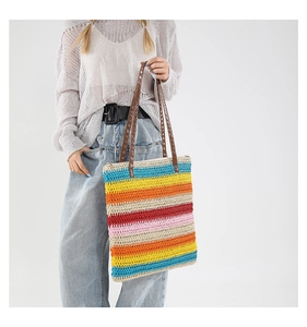 Dettaglio borsa tote intrecciata colorata con strisce a contrasto e manici marroni
