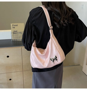 Détail du sac en cuir PU rose nacré avec un ornement papillon en métal argenté brillant