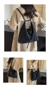 Detail of black pleated bag featuring lace-up bow and silver chain strap