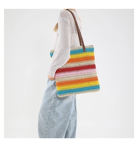 Dettaglio della borsa tote intrecciata a righe colorate con manici in pelle marrone