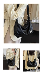 Vue détaillée du charme papillon argenté et du cuir souple plissé sur le sac noir