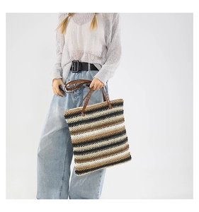 Dettaglio borsa tote intrecciata a righe tricolore con manici sottili marroni