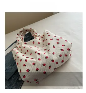 Detail view of corduroy tote bag with red strawberry print and soft textile texture