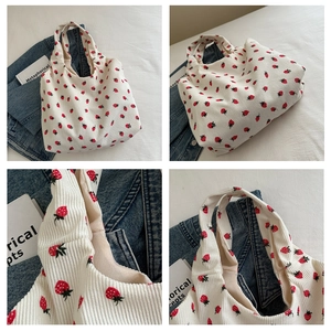 Detail of white corduroy tote bag featuring red strawberry embroidery and inner lining